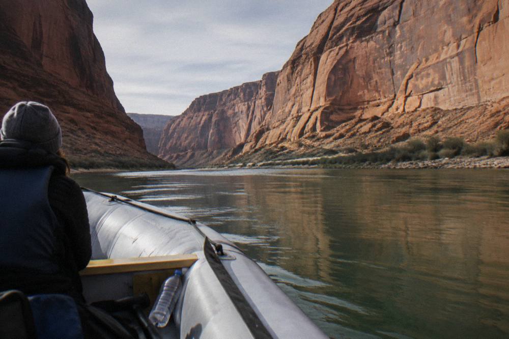 A motor raft floating on calm green water between sheer sandstone walls in Glen Canyon